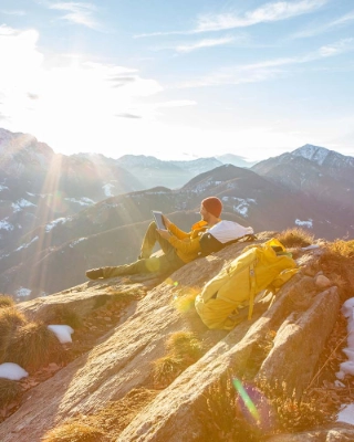 Mann auf einem Felsen, der waehrend seiner Wanderung eine Pause macht und sich entspannt, dient als Symbolbild für die Themen Anlegen und Kassenobligation.